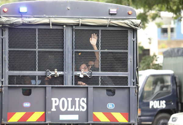 嫌犯乘坐警方大卡车时，还隔着栏门叫嚣要摄影记者“多拍一点”。
