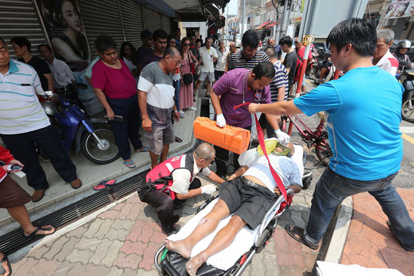 医护人员与游客协助将老翁抬上救护车。 