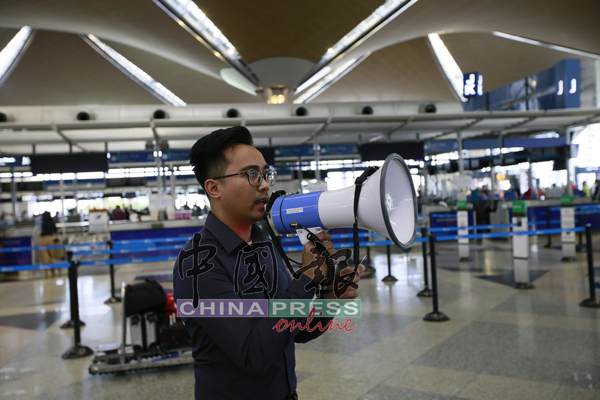 机场职员以扩音器报告办理相关航班的登机柜台位置。