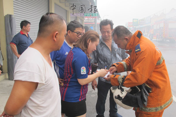 沈美发（右2）及家人向消拯员讲解店内的构造，方便消拯员进入救火。