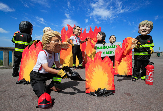 七国集团峰会登场前夕，示威者在法国滨海小镇比亚里茨，戴着“美国总统特朗普”和“其他国家领袖”的面具，抗议亚马逊林火。（美联社）