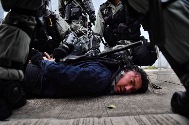 镇暴警察周六在香港九龙湾逮捕一名示威者，并压倒在地。（法新社）