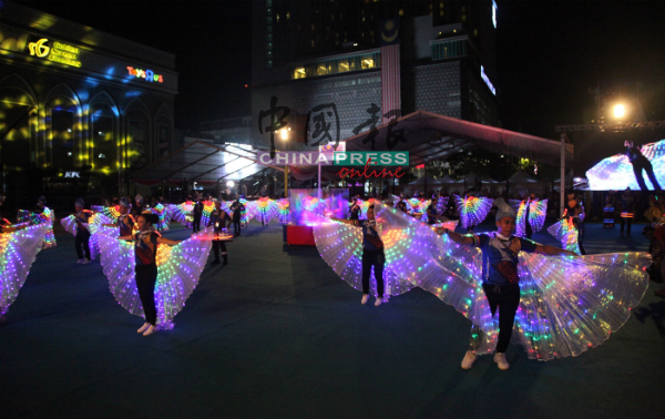 参演者身穿色彩缤纷的服装，在甲市英雄广场大操场翩翩起舞。