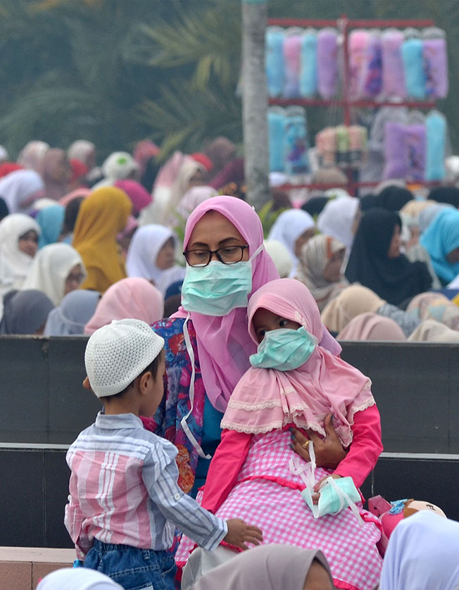 穆斯林周日在北干峇鲁清真寺参加哈芝节祈祷时，一家大小都戴口罩防霾害。（法新社） 