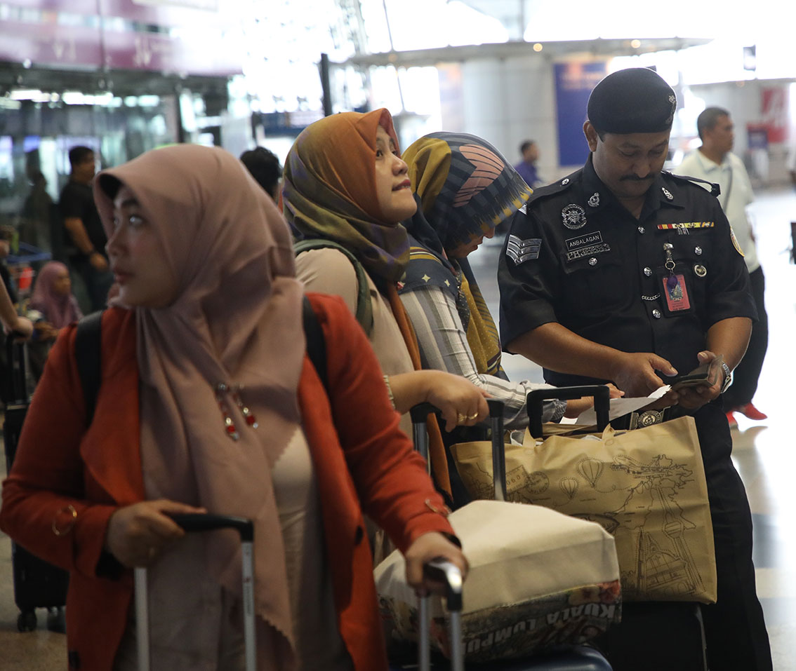机场警察（右）帮忙乘客查找登机柜台。