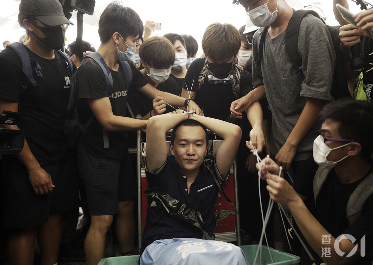 一名中国男子被示威者绑上索带。（HK01）