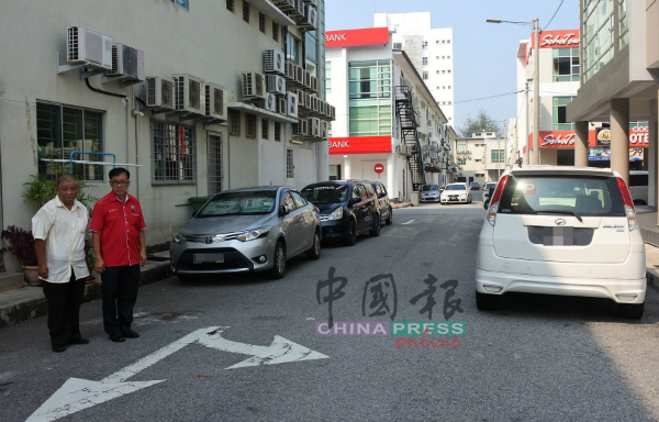 多辆汽车违规泊在后巷，随时接罚单。左起为邓志康、陈劲源。