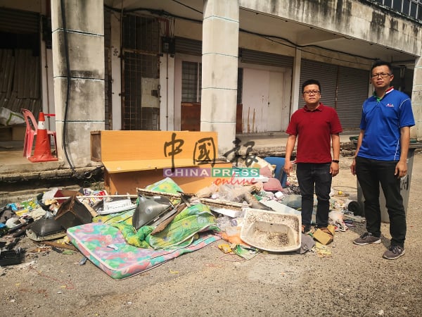 李春源（左起）和罗舜生展示店前的大件垃圾，包括有床褥、洗手盆、木板等。