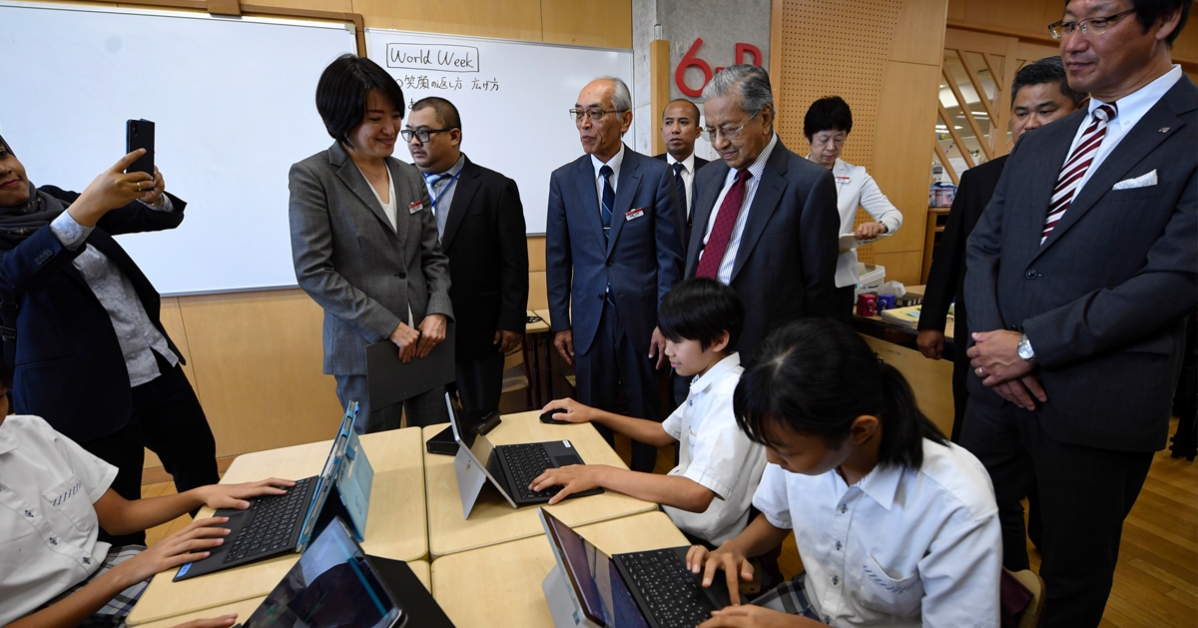 马哈迪在旁观察小学生如何使用电脑在课堂上学习。