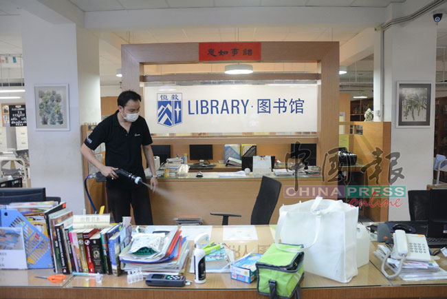 邓振胜在恒毅宏愿楼的图书馆喷洒二氧化钛，进行消毒工作。