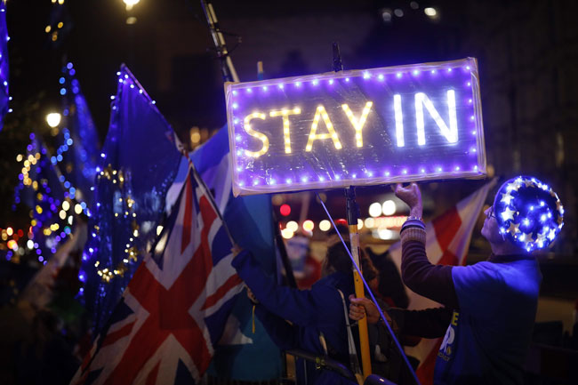 游行人士周一晚上在英国国会外高举欧盟旗，并竖立牌子呼吁“留下”。（法新社）
