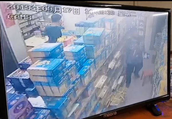 胸前挂着小背包的男子（右者），当时手里拿着两包奶粉，鬼鬼祟祟地走到药材店后排货架角落。