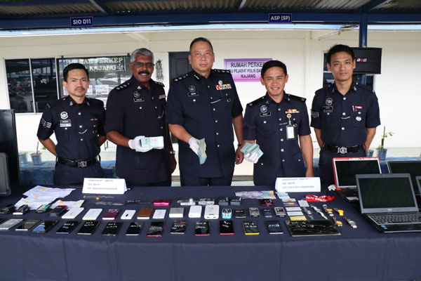 阿末查菲尔（中）与立功警员展示所起获的贼赃，当中包括现款、手机和笔记型电脑。