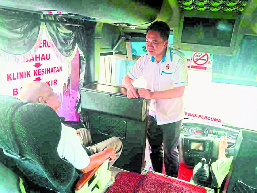 张聒翔（站者）向乘客了解对巴士服务的满意度。