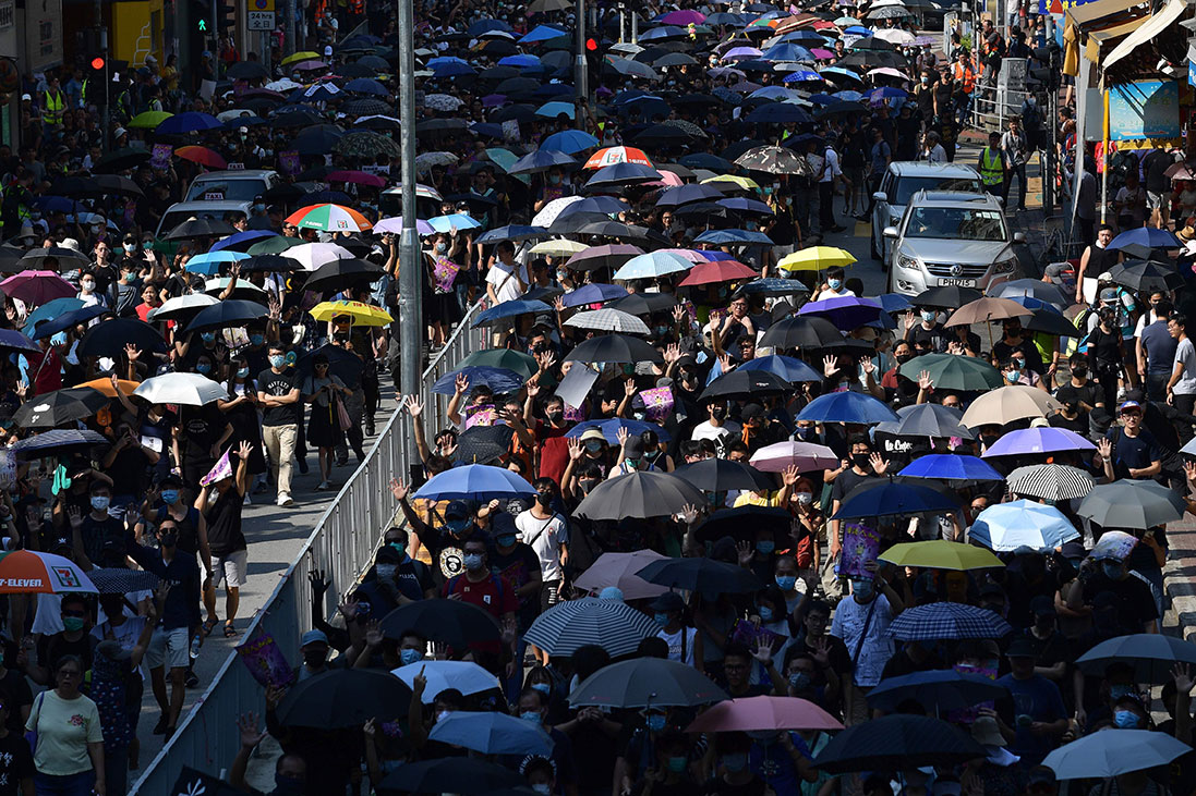 游行队伍周六下午起步，人群撑起伞前往屯门政府合署外。（法新社）