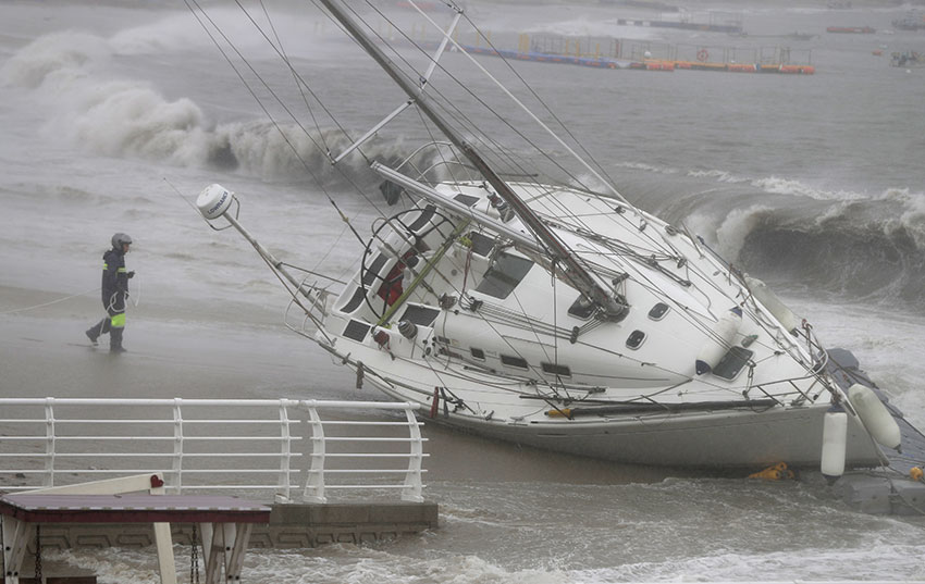 受台风影响，韩国蔚山市海岸刮起强风巨浪，一艘游艇被吹歪，搁浅海岸边。（欧新社）