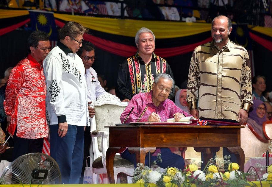 马哈迪（坐者）在2019年马来西亚日特别纪念册上签名。左起为沙巴首长沙菲益阿达、砂首长阿邦佐哈里和哥宾星（右）见证。