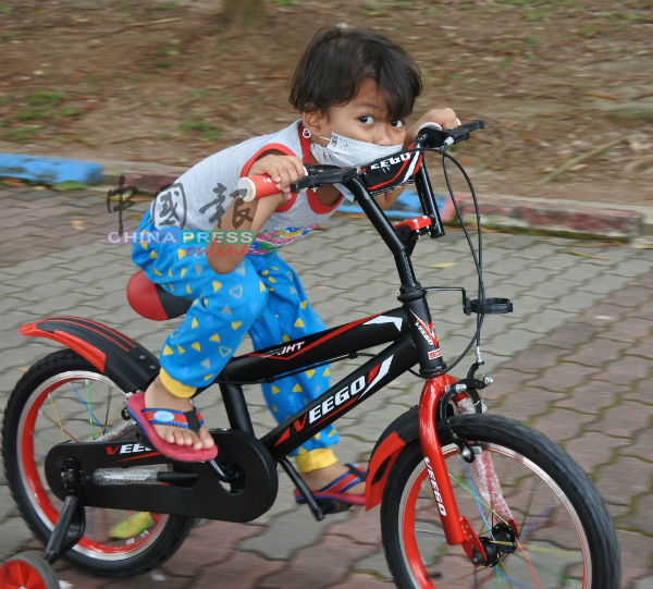 戴上口罩的小孩，骑脚车玩乐。