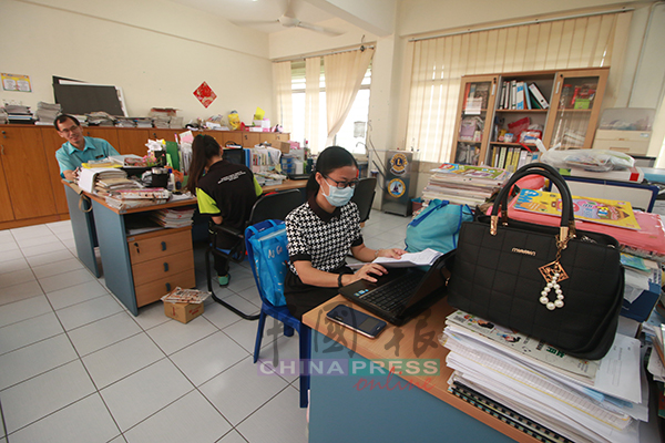  学校办公室里，教职员照常上班，有者戴上口罩防烟霾。