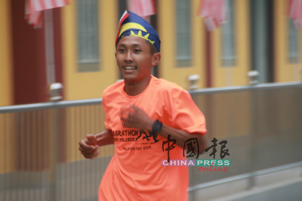 1名参加跑步比赛的马来青年用国旗做成头饰参加比赛。