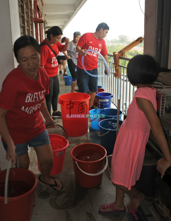 组屋居民与志工忙着派水、取水。