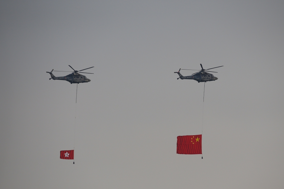 悬挂国旗及区旗的飞行服务队直升机飞越维港上空。（欧新社）