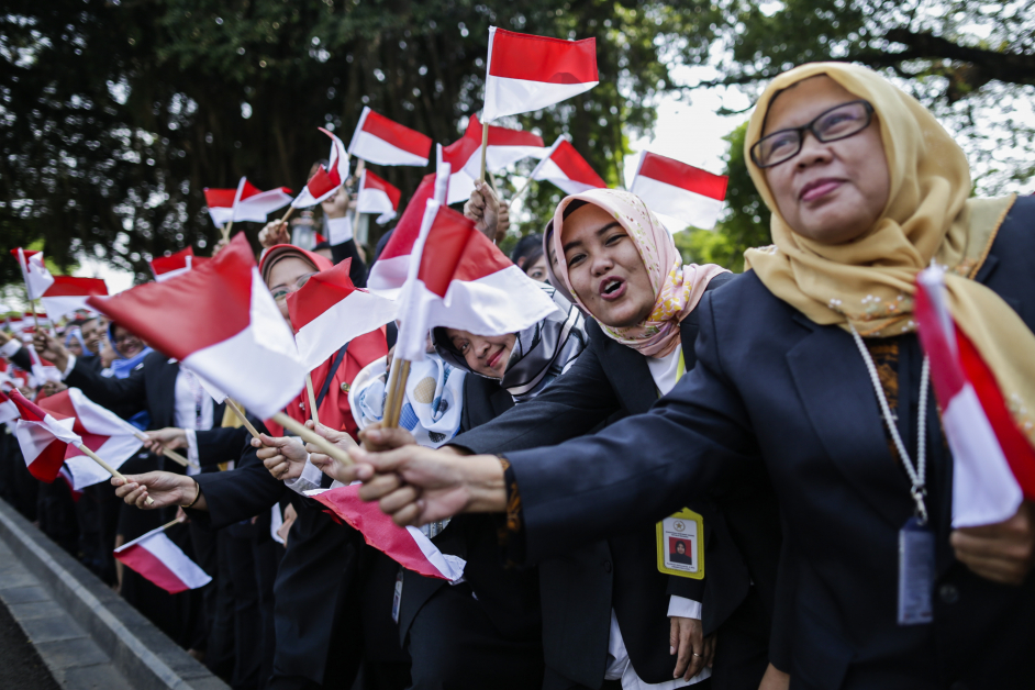 印尼总统府职员挥舞印尼国旗，庆祝佐科威宣誓就任。（欧新社）