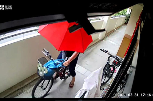 女邻居经常撑着红色雨伞，在走廊骑脚踏车。