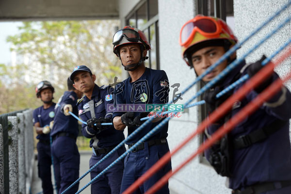 拯救团队努力拉着绳索，协助一名团员用绳缆越过建筑物另一侧。