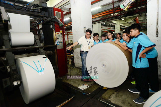王振添（左）展示访问团，用来印刷报纸的卷筒纸。