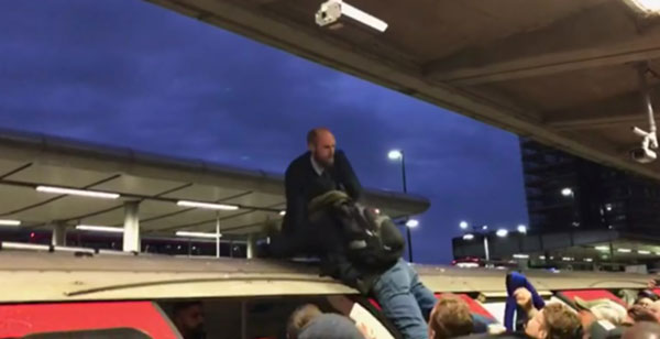 周四在伦敦景宁镇站爬上地铁车顶的示威者，被人抓住脚拉下来。（美联社）