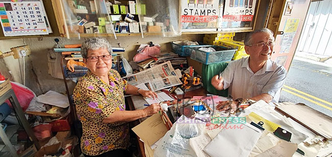 郭宝珠（左）在老店内，开了一张捐助波中1万令吉的支票，右为莫泰波。