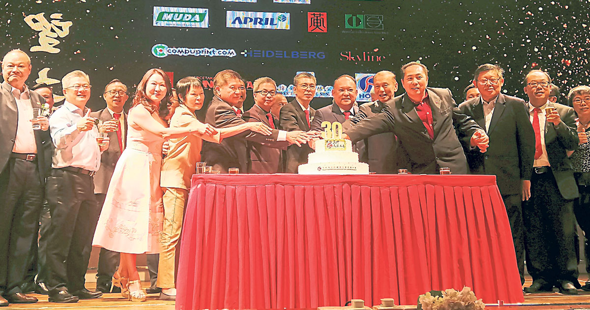 郭献谋（前排右3起）和黄伟连等理事，齐切生日蛋糕，庆祝马来西亚印刷公会柔佛分会成立30周年。
