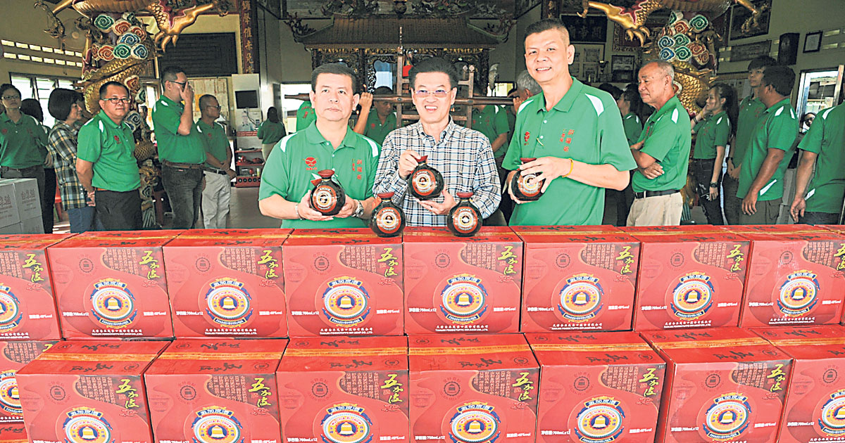 陈清专（左起）、陈祈福和陈承耀与新购的50箱五加皮酒合照。