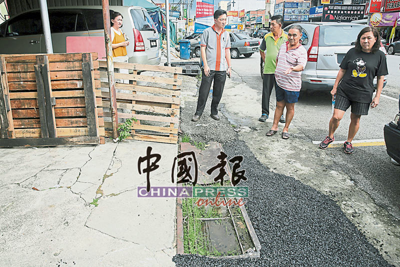 谢琪清（左2）在商家带路下，巡视商家自费的排水沟铺盖。