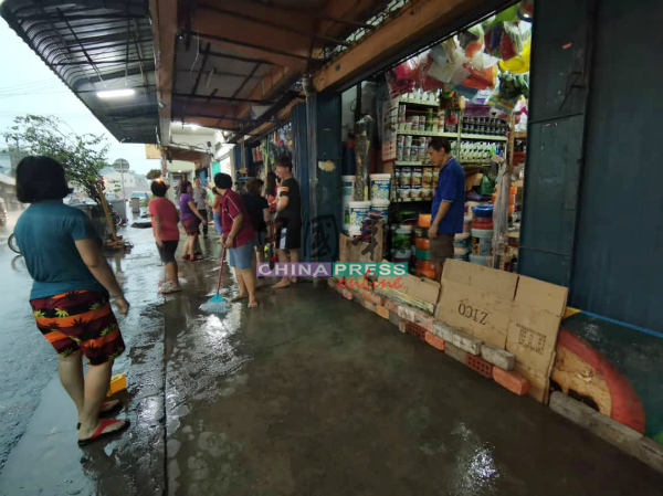 商家以砖块及各式物件挡在店前，试图阻拦水流进店。