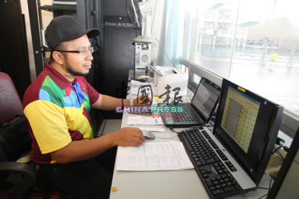 赛事技术协调员莫哈末礼祖安从监控室电脑荧幕上观看比赛成绩。