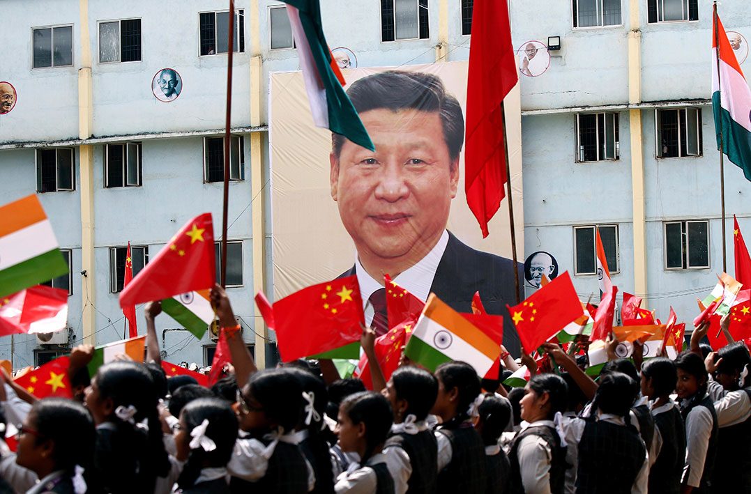 校园围墙挂上习近平大头照，学生们挥舞印度和中国的国旗。（美联社）