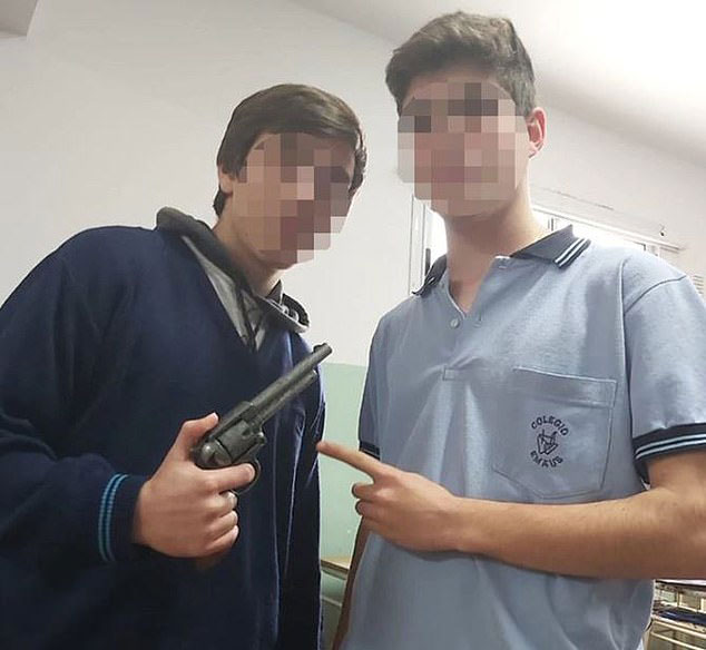 男同学（左）恶作剧后，持玩具手枪留影。
