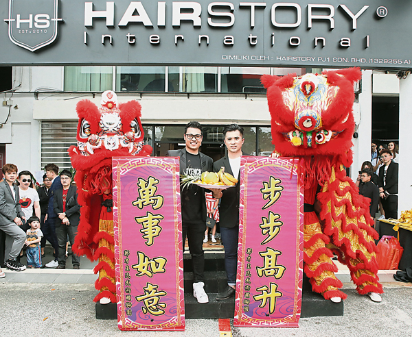 ■李烔良（左）和黄子玮在Hairstory International分店前，与象征富贵吉祥的醒狮合影。