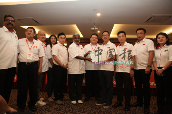 元老级党员阿都拉曼（左6起）在颜炳南见证下，代表新党员移交入党申请表格给刘华才。
