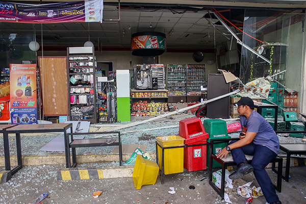 南达沃省迪戈斯市一间店铺在地震中损毁，店主周四在店外看管店铺。（法新社）