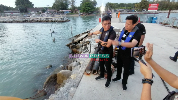 诺依占（左）到甲市丹绒吉灵海南村渔民码头，发现不法公司把防浪堤改为非法码头。