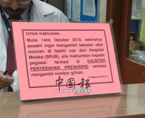 中央医院药房柜台出示通告，鼓励病人申请到政府诊所取药。