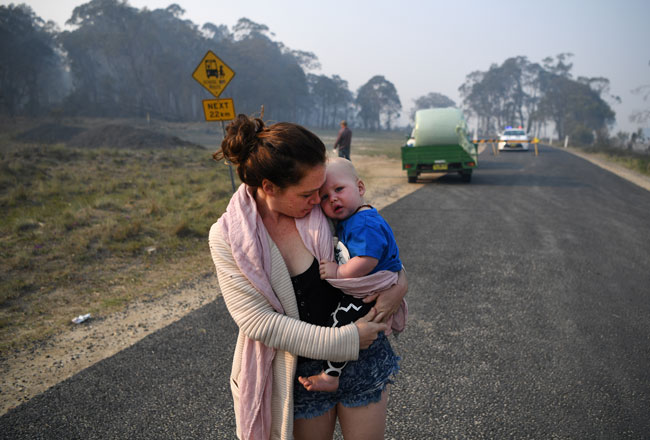在新南威尔斯州的格伦因尼斯，一名女子抱着孩子撤离。