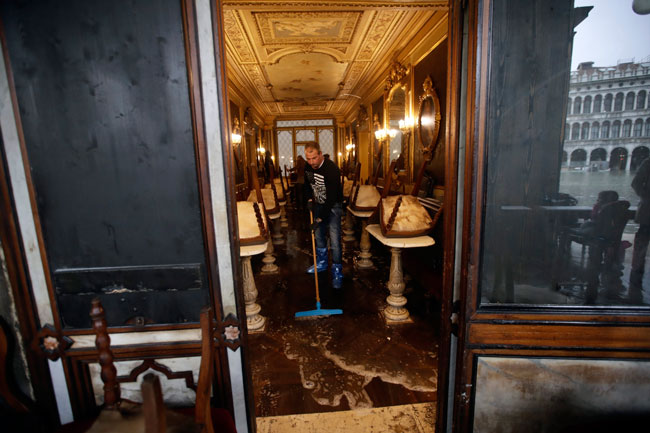 历史悠久的佛罗里安咖啡馆淹水，一名男子周三在清理污水。（美联社）