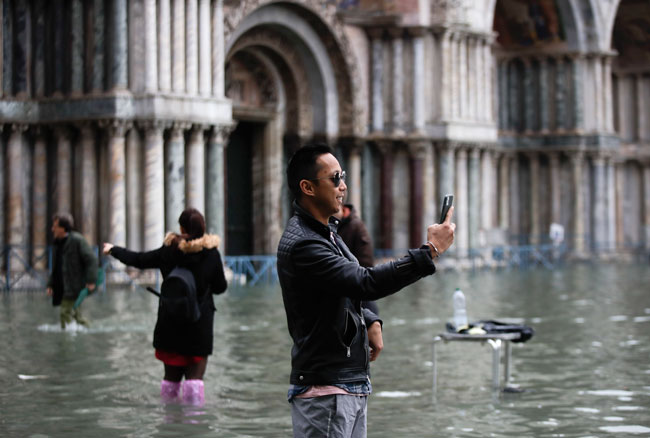 游客周三在淹水中的圣马可广场拍照。（美联社）