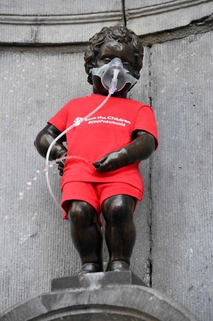 比利时地标“尿尿小童”雕像周二穿上红色衣服，戴着氧气罩，纪念世界肺炎日。（法新社）