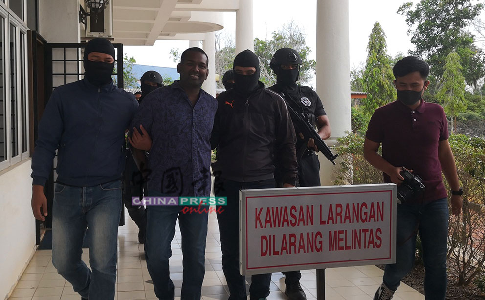 迪兰（左2）被反恐部队带上法庭时，面带微笑面对媒体镜头。
