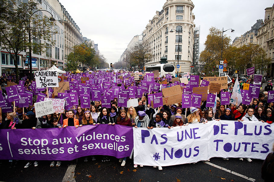 游行人士高举紫色标语牌和旗帜，呼吁政府正视妇女家暴遇害问题。（美联社）